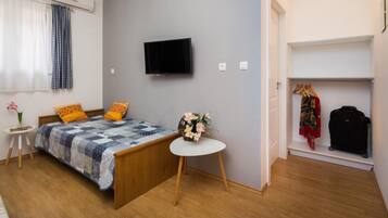Ein Schlafzimmer mit einem Bett, einem Fernseher, einem kleinen Tisch mit einer Vase, einem Kleiderschrank und einem Koffer.