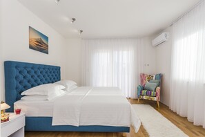 Un dormitorio con una cama grande, una mesita de noche, una silla y un cuadro en la pared.