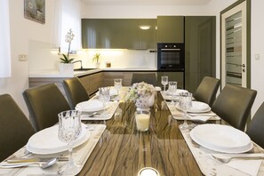 Une table à manger pour six personnes, avec un plateau en marbre, entourée de chaises aux couleurs sombres.