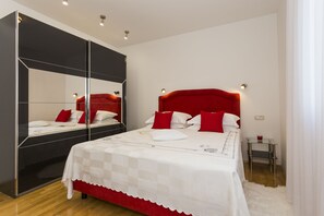 Une chambre à coucher moderne avec un grand lit, une armoire à miroir et une table de chevet avec une lampe.