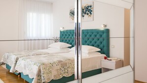 Une chambre avec deux lits, un miroir et une table de chevet avec une lampe.