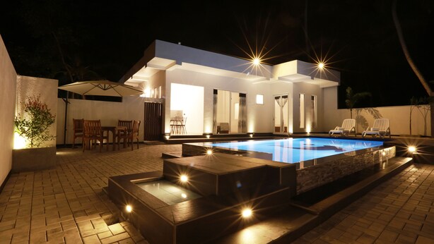 A modern outdoor pool area with a hot tub, a dining area with chairs, and a covered seating area. - FIVE BEDROOM DELUXE VILLA WITH PRIVATE SWIMMING POOL (Habaraduwa)