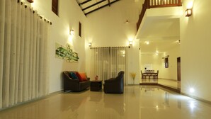 A spacious living area with a high ceiling, a sofa set, a coffee table, and a dining area with chairs. - FIVE BEDROOM DELUXE VILLA WITH PRIVATE SWIMMING POOL (Habaraduwa)