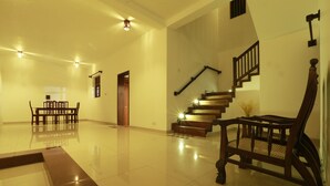 A spacious, well-lit interior with a polished floor, a staircase, and a dining area with chairs and a table. - FIVE BEDROOM DELUXE VILLA WITH PRIVATE SWIMMING POOL (Habaraduwa)