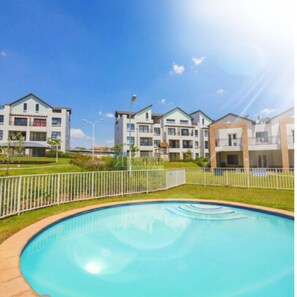 Un complejo residencial de arquitectura moderna, con piscina y valla blanca.