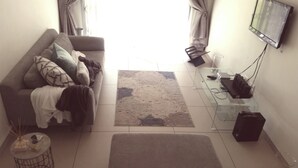Ein Wohnzimmer mit einer Couch, einem Couchtisch, einem Fernseher und einem kleinen Beistelltisch.