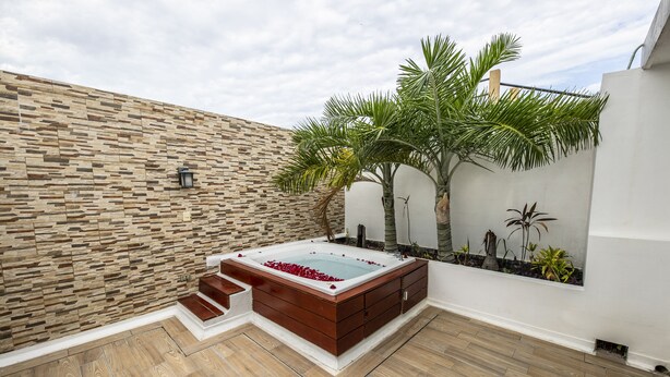 Ein Wellnessbereich mit Whirlpool, Holzstufen und einer Steinwand.