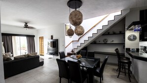 Ein modernes Wohnzimmer mit einer Couch, einem Esstisch und Stühlen. Eine Treppe führt zu einer Küchenzeile.