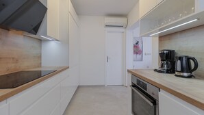 Ett modernt kök med vita skåp, en bänkskiva i trä, en inbyggd ugn och en kaffebryggare.