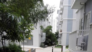 Un sendero pavimentado en una zona residencial con edificios modernos, vegetación y unidades de aire acondicionado exteriores.