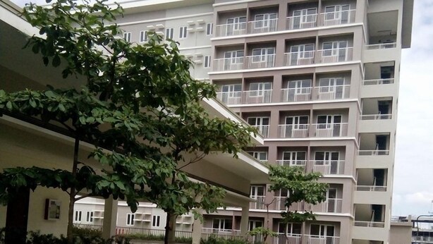 Niño corriendo sobre un sendero de hormigón frente a un edificio residencial de varios pisos con balcones.