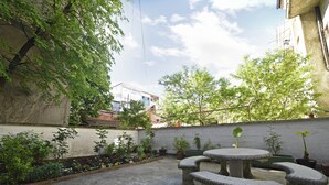 A courtyard with a round stone table and benches, surrounded by potted plants and a low wall. - Cozy two bedrooms apartment in vivid neighborhood  (Zagreb)
