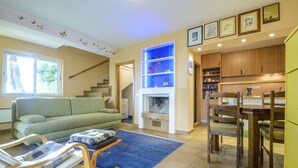 Un salon comprenant un canapé, un fauteuil à bascule, une cheminée et un coin repas avec une table et des chaises.