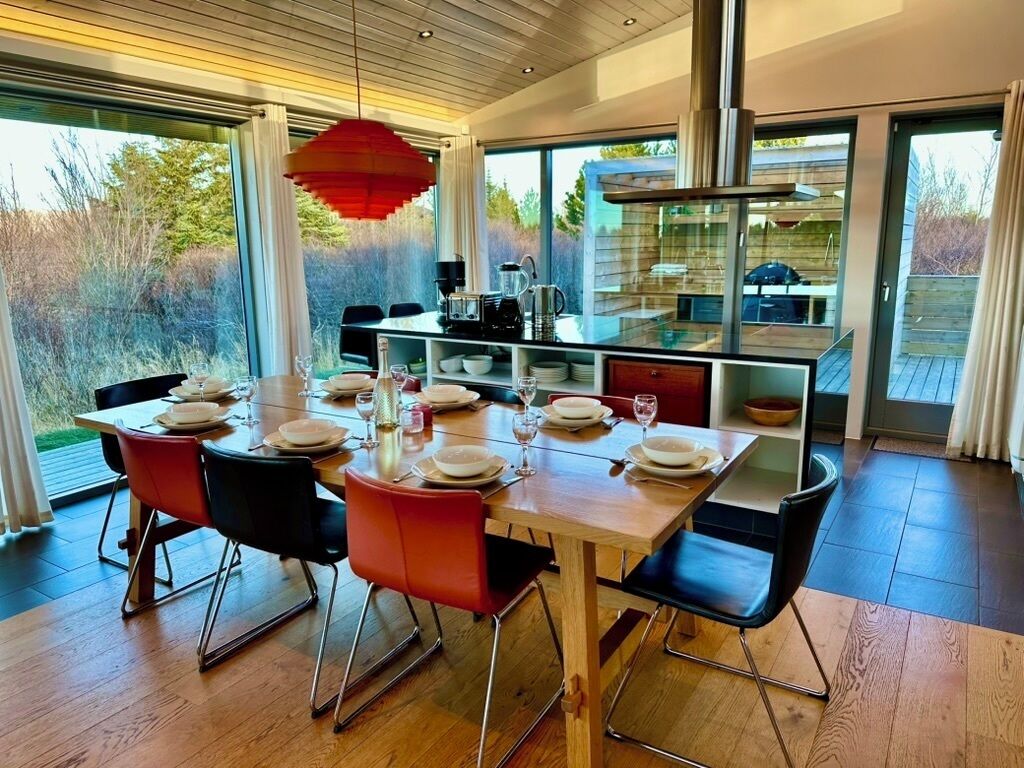 Un comedor moderno con una mesa de madera dispuesta para cuatro personas, rodeada de sillas.