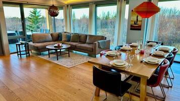 Un'area pranzo moderna con un tavolo in legno apparecchiato per sei persone, una poltrona e vista all'esterno.