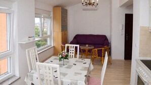 Ein Essbereich mit Tisch, Stühlen, einem violetten Sofa und einer Deckenleuchte.