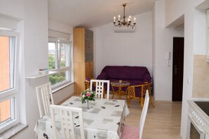Un coin repas comprenant une table, des chaises, un canapé violet et un lustre.