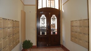 A hallway with a wooden double door, beige lockers on either side, and a potted plant in the center.