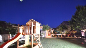 A playground with a slide and climbing structure, surrounded by a grassy area and trees. - Amazing villa near Split with private pool and playground!!!  (Žrnovnica)