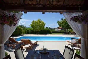 Un espace aménagé au bord de la piscine, avec des chaises longues et une table, donnant sur le bassin.