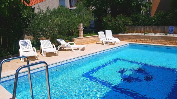 A swimming pool with white lounge chairs and a metal ladder. - MARTINA 3-star*** Apartment with POOL (Banjole)