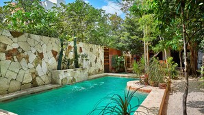 A swimming pool with a stone wall and surrounding greenery.