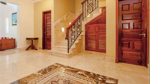 A grand staircase with a marble finish, flanked by wooden doors with glass panels, leading to an upper floor. - Villa Miramar Aventuras – Luxury Tropical Villa in the Mayan Riviera (Puerto Aventuras)