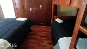 Una habitación con dos camas, un armario y una televisión.