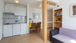 Un espai habitable pràctic amb cuineta, zona de dinar i sofà.