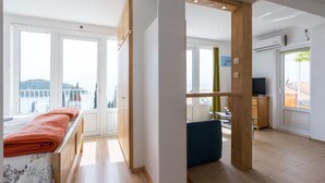 Habitació d'hotel moderna amb balcó, terres de fusta i televisió.