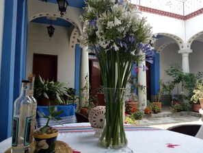 Ein Innenhof mit Esstisch, umgeben von Topfpflanzen und einer dekorativen Vase.