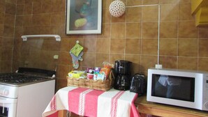 Une cuisine équipée d’un four à micro-ondes, d’un grille-pain et d’un panier rempli de divers objets posé sur le comptoir.