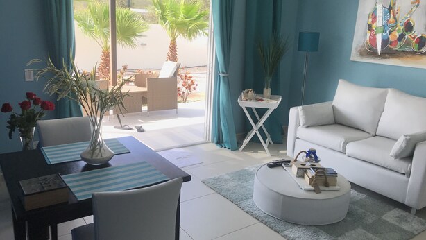Un salon moderne avec un canapé blanc, une table basse ronde et un coin repas agrémenté d’un set de table à rayures.
