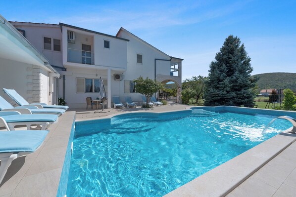 A swimming pool with lounge chairs, a patio area, and a large tree. - Villa Almas with swimming pool, summer grill house and tennis court (Neoric)
