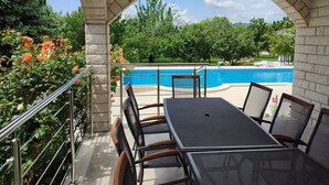 A covered patio with a pool view, outdoor seating, and a stone archway.
