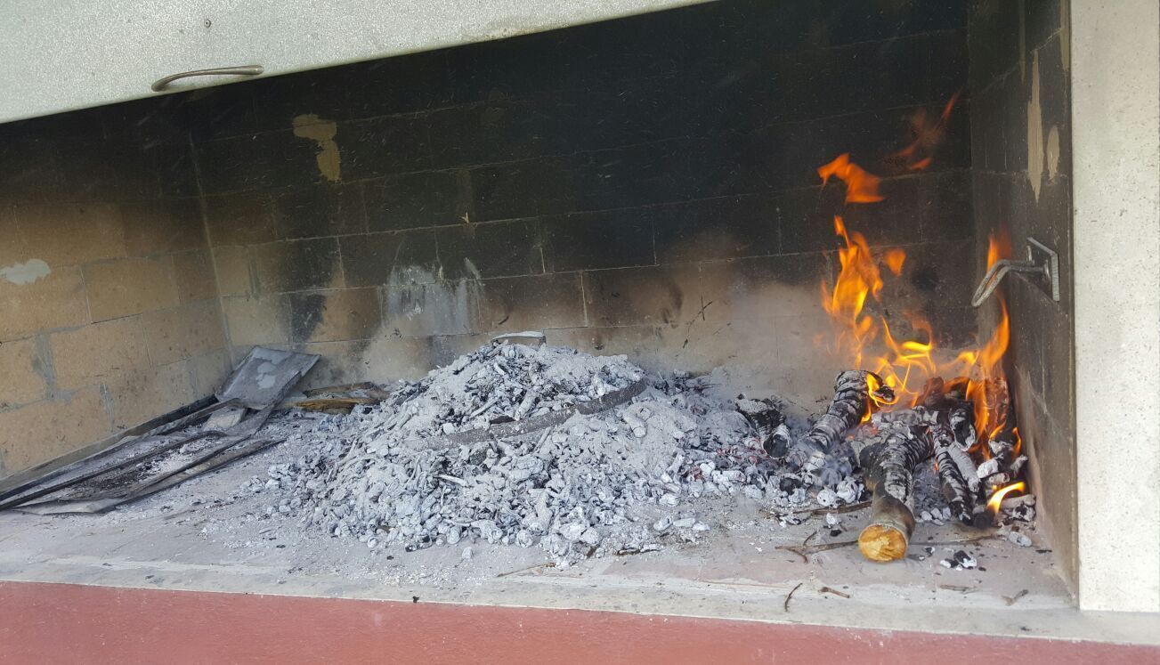 A fireplace with burning logs and ash.