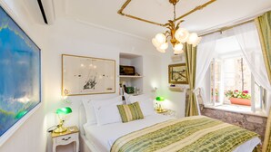 Un dormitorio con cama, lámparas de noche, mesita de noche, ventana con cortinas y una pared decorada con obras de arte.