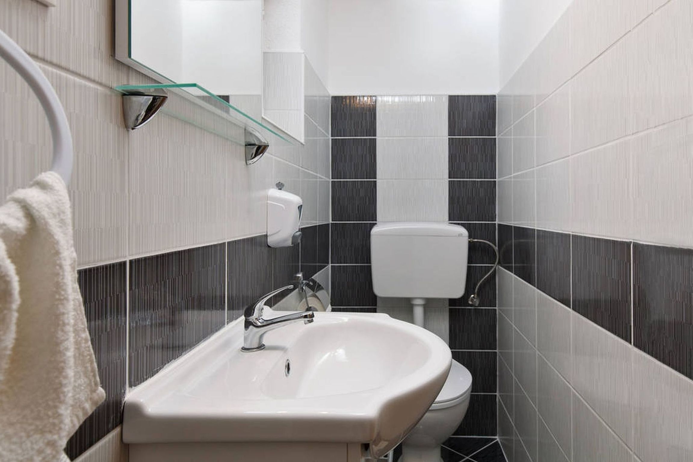 Une salle de bain avec un lavabo blanc, des toilettes et une étagère en verre au-dessus du lavabo.