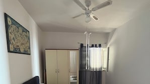 A bedroom with a bed, a wardrobe, a ceiling fan, and a window with curtains. - Apartment VITA in Soline near the city of Dubrovnik with a beautiful view (Plat)