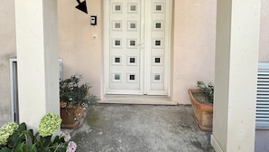 A building entrance with a wooden ceiling, a white door with glass panels, and potted plants on either side. - Apartment VITA in Soline near the city of Dubrovnik with a beautiful view (Plat)