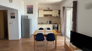 A compact living space with a dining area, kitchenette, and a TV on a wooden cabinet. - Apartment VITA in Soline near the city of Dubrovnik with a beautiful view (Plat)