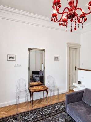 A modern living room with a chandelier, a sofa, a coffee table, and a mirror.