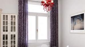 A dining area with a white table, clear chairs, a chandelier, and a cabinet with glass doors. - Deluxe apartment with super Wifi in city center (Budapest)