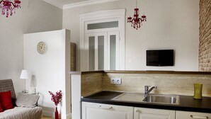A compact kitchen with a sink, a flat-screen TV, and a clock on the wall. - Deluxe apartment with super Wifi in city center (Budapest)