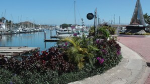 A marina with boats docked, a pedestrian path, and a modern sculpture. - Greate apartment at Nuevo Vallarta (Las Jarretaderas)