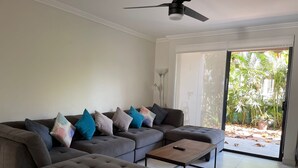 A modern living room with a sectional sofa, a coffee table, and a ceiling fan. - Greate apartment at Nuevo Vallarta (Las Jarretaderas)
