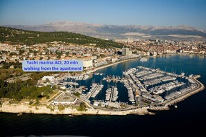 A marina with numerous boats docked, surrounded by a cityscape and mountains in the background.