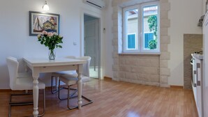 Un coin repas avec une table et des chaises blanches, un vase de fleurs et un tableau accroché au mur.