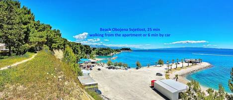 A beach with a parking area and a path leading to the beach.