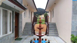 Ein Innenhof mit einer zentralen Fontäne, Blumentöpfen und Blick auf einen Hügel.